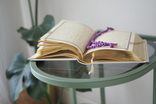 Open quran with beads on a green table in a room