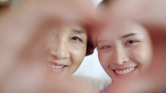 Close-up of smiling asian mother and daughter expressing love, happiness, and strong family relationship in soft natural light.

