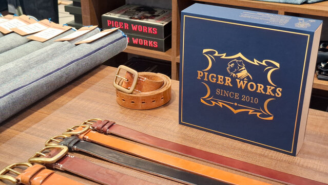 Premium Piger Works handcrafted leather belts and high quality raw denim jeans apparel collection displayed on wooden table on April 27, 2026 in Bangkok, Thailand