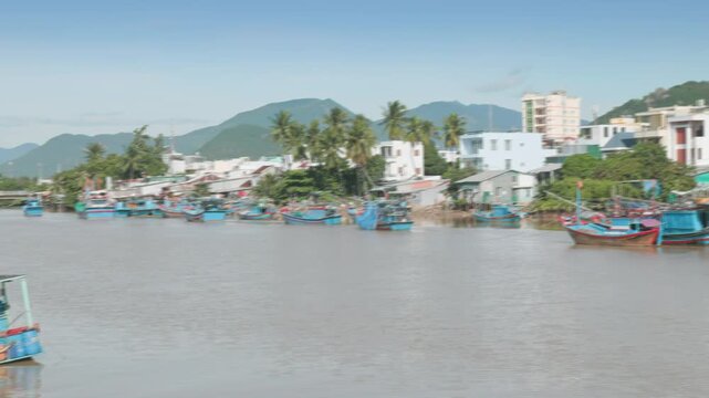 Fishing boats are moored in Cai River, Nha Trang, Vietnam. The boats are painted in bright colors and are ready for the day's catch. The scene is peaceful and serene.