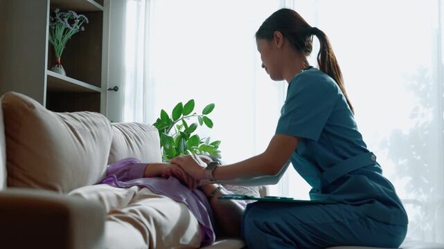 Professional caregiver providing home healthcare service, checking pulse and monitoring elderly patient in a comfortable living environment.
