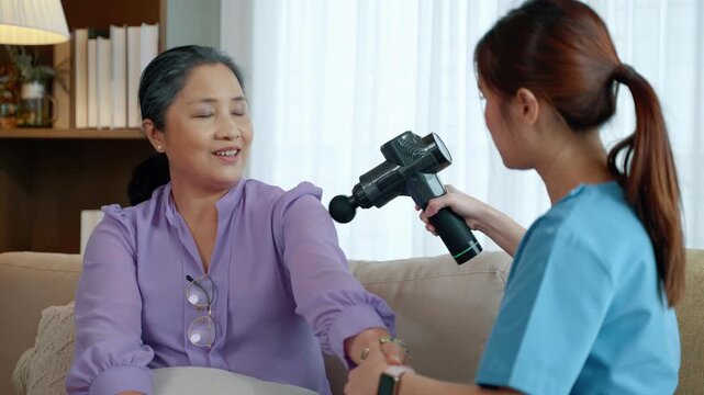 Close-up of physiotherapy session using massage gun to relieve muscle tension and improve circulation for elderly patient.
