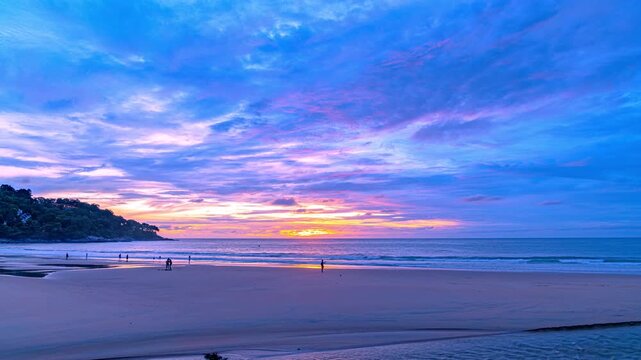 Time lapse sky turns yellow to orange and red over the sea.
The sun rays cast a warm glow on the landscape. The horizon is painted in hues of red and purple. The sky is ablaze with color