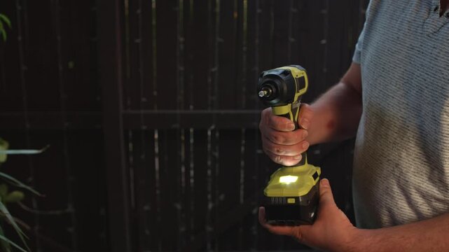 Man inserting battery into cordless drill and demonstrating bit rotation showing power tool operation testing performance and functionality for repair and construction tasks