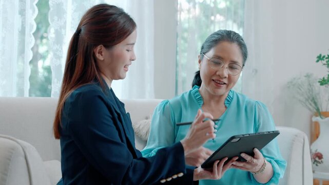 Asian female client signing agreement papers with financial advisor, representing investment planning, contract agreement, and financial decision making.
