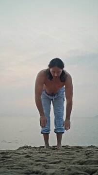Man Performing Forward Bend On Sandy Shore At Sunrise, Barefoot And Focused, Calm Ocean Backdrop With Soft Morning Light, Wellness And Mindfulness Practice In Natural Coastal Setting