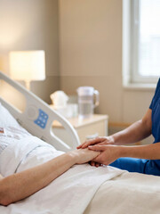 Obraz premium Compassionate Healthcare Worker Holding Patient's Hand in Hospital Room Cinematic Melancholic