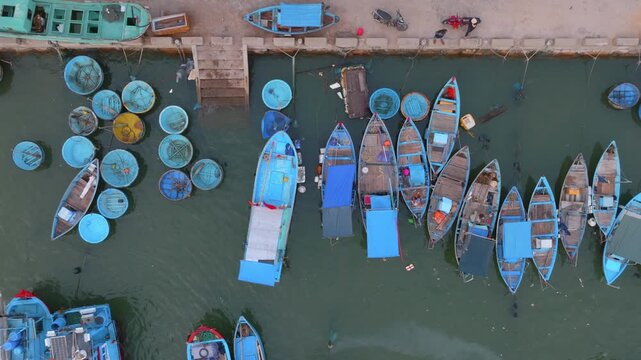 A fleet of traditional Vietnamese fishing boats and coracles are moored in a harbor in Nha Trang, Vietnam. The boats are ready for the day's catch.