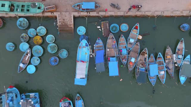 A fleet of traditional Vietnamese fishing boats and coracles are moored in a harbor in Nha Trang, Vietnam. The boats are ready for the day's catch.