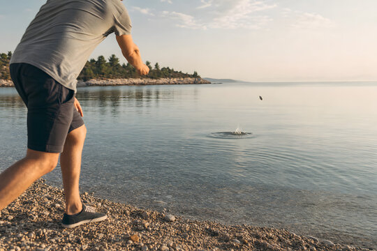 Low angle view of a person skipping stones across calm sea water