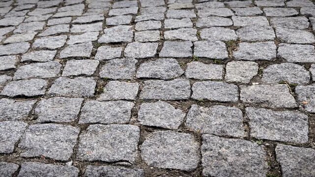 Horizontal close up of grey granite cobblestone pavement, architectural stone texture, urban road surface, construction material, outdoor pathway, candid style, natural stone pattern.