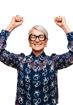 stylish senior caucasian woman with silver hair and thick black spectacles, wearing a geometric navy silk blouse, raising fists ecstatically against a coral peach studio backdrop. concept of