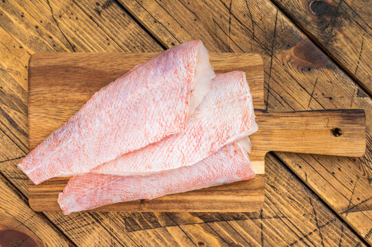 Raw redfish fillets on wooden cutting board. Fresh seafood ingredient on rustic wooden background with copy space.