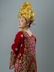 Naklejka premium Young Indonesian Asian Woman in Red Embroidered Dress With Ornate Gold Headdress Wearing Traditional Cultural Costume