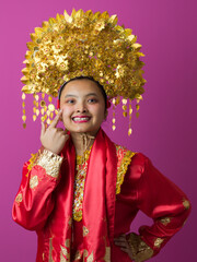 Naklejka premium Young Indonesian Asian Woman Wearing Ornate Gold Headdress and Red Traditional Costume Celebrating Cultural Festival