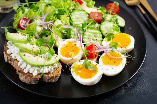 Healthy Keto Salad with Avocado and Soft Boiled Eggs on Dark Background