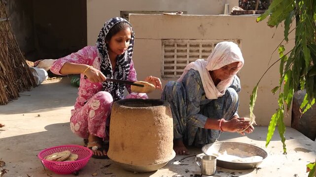 Rural Indian women preparing food on traditional chulha stove at home. village lifestyle, home cooking, use of firewood,. traditional cooking methods, culture and daily life in village of India