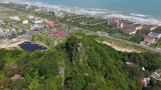 Vietnam, Da Nang Aerial Coastal Resort View Da Nang Vietnam With Redroof Hotels, Reflective Pond, Lush Limestone Hill, Palmlined Avenues And Turquoise Ocean Waves Under Bright Sunlight
