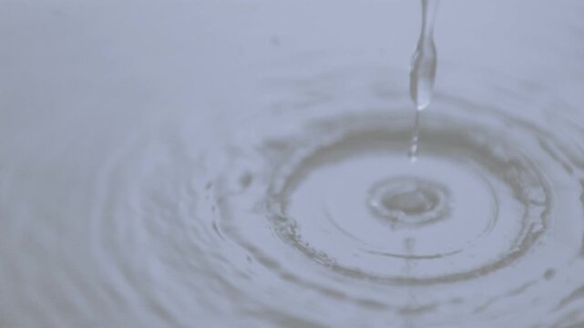 Water stream pinching off droplets falling and hitting surface forming ripples and jets for design