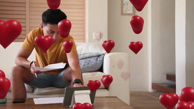 Man putting phone down tapping tablet marking docs while red hearts floating before him for promo