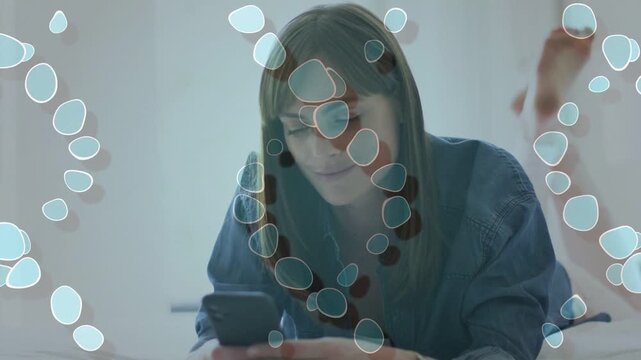 Woman lying on bed tapping phone, scrolling messages and reading, tech overlay drifting over frame