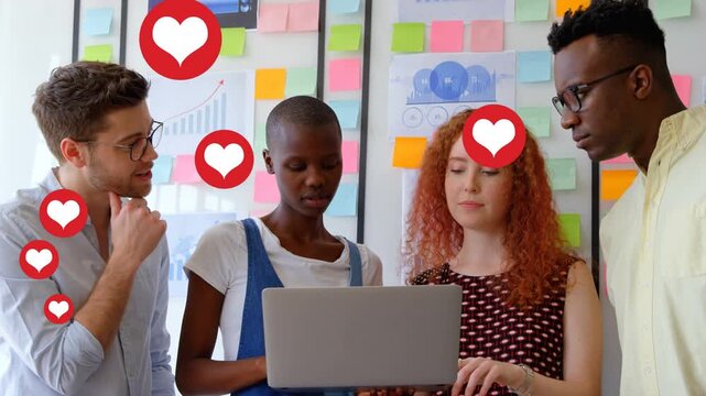 Business team reviewing deck on laptop, lead woman typing, causing hearts rising over notes wall