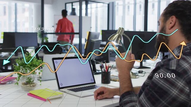 Seated man gesturing by lamp while graphs moving across desk on data update showing finance trend