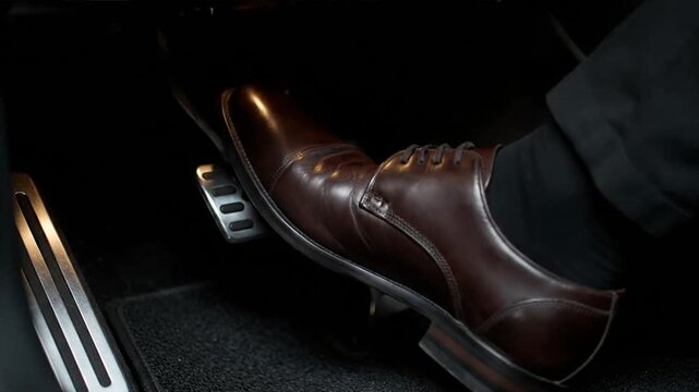 A man's foot presses the accelerator pedal in a car.