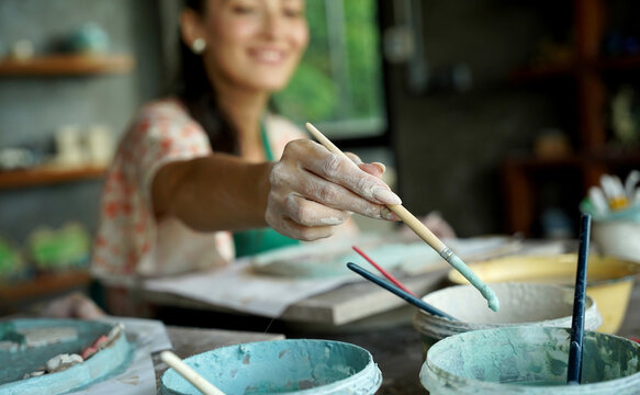 A young woman makes a ceramic plate in a workshop
