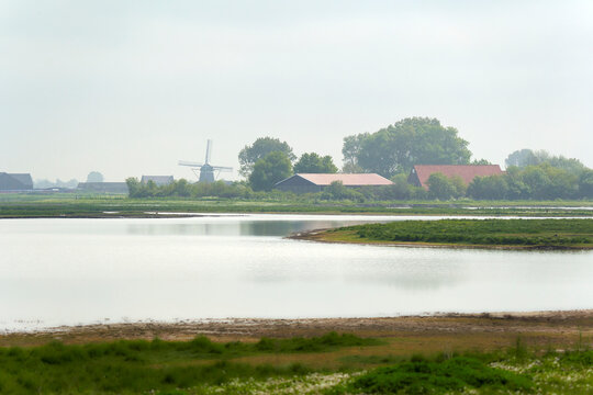 National Park in Holland. Landscape in spring with fog. Windmill an farm. Netherlands, Zeeland, Oosterschelde.