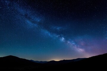 Obraz premium A vast, star-filled night sky stretches over silhouetted mountain ridges
