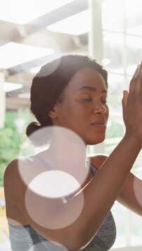 Vertical video: Woman raising arms to yoga prayer, centering with lens flares crossing near her