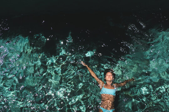 Relaxed woman floating in sparkling villa pool, Uluwatu, Bali