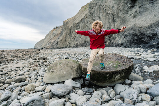 Happy child exploring rocky coast with fossils in New Zealand