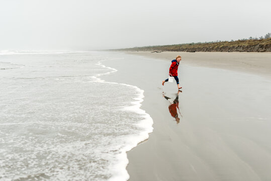 Smiling child playing on a beach on foggy day