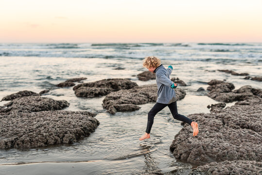 Curly haired child jumping into water at beach