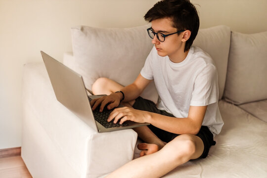Focused adolescent typing on laptop computer