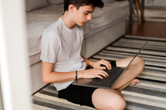 Focused teenage boy typing on laptop