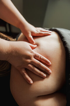 Close-up of therapist hands pressing into client's back, warm light