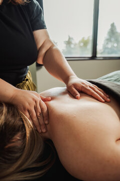 Therapist hands on client's neck and upper back near bright window