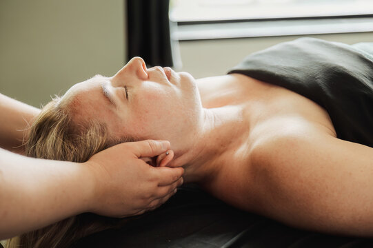Woman lying on massage table, eyes closed, neck treatment
