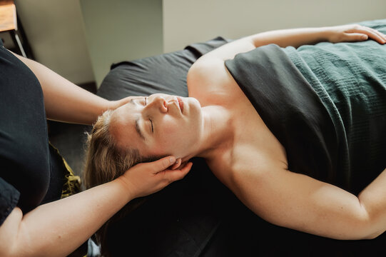 Woman with eyes closed receiving neck massage, lying on table