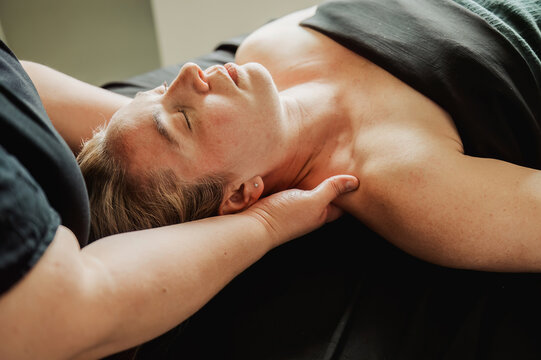 Relaxed woman receiving neck massage, eyes closed, close-up