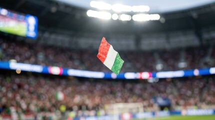 Obraz premium Small italian flag floating in air over blurred stadium crowd during intense football match.