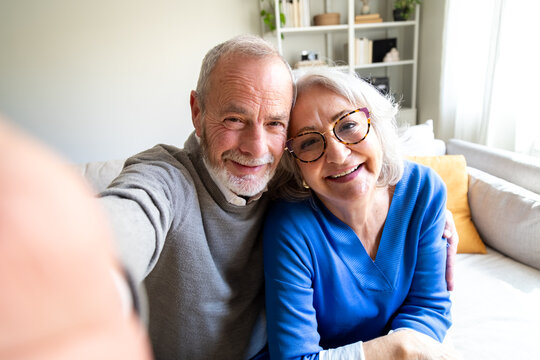 Happy senior couple taking a selfie on the sofa at home