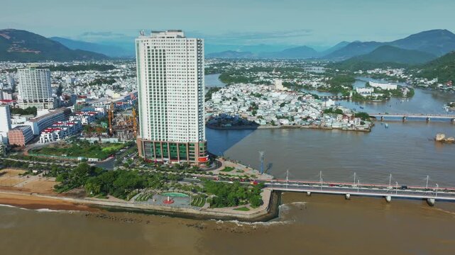 Nha Trang, Vietnam - An aerial view captures the Han River and the city skyline, featuring the iconic Dragon Bridge and a modern skyscraper, showcasing urban development and riverside life.