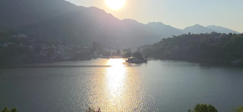 Bright sunlight glows over Bhimtal Lake surrounded by gentle hills and quiet atmosphere