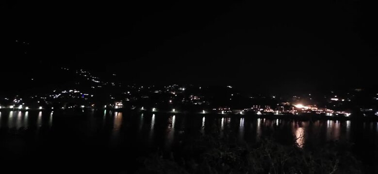 Lights from far buildings glow across Bhimtal Lake under dark night sky