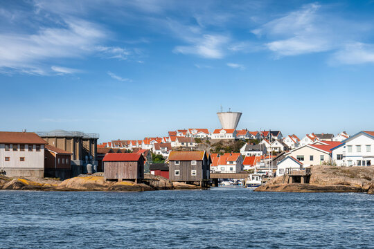 Sm&ouml;gen island from sea with industrial buildings and tanks at Omholmen, traditional boathouses on rocks and modern water tower, Bohusl&auml;n, west coast Sweden