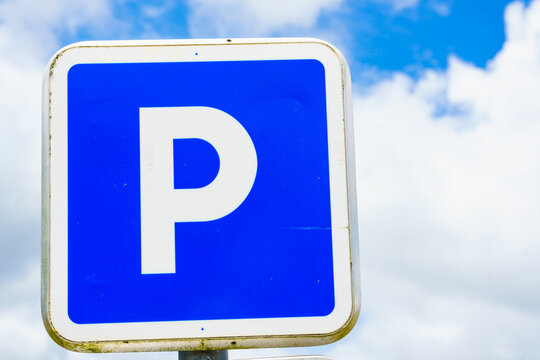 Parking sign under blue sky with fluffy clouds indicating available parking space in a public area